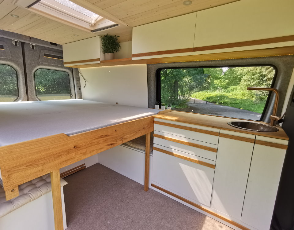 Camper ausbauen lassen - wir holen für dich das Maximum raus: Auch beim Bett. Hier gelöst durch ein Ausziehbett mit 2 Metern Länge.